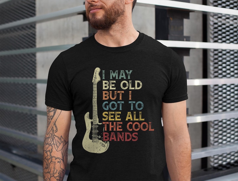 May include: A black t-shirt with a vintage-style graphic of an electric guitar and the text "I may be old but I got to see all the cool bands".