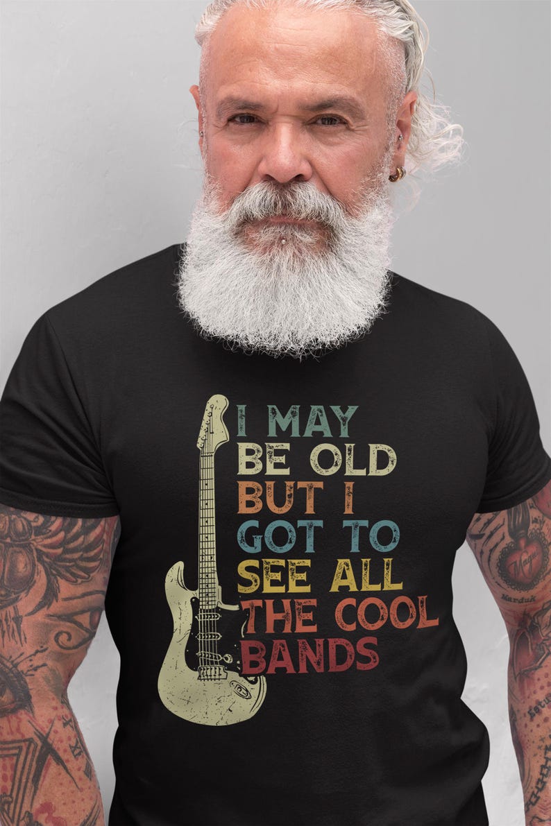 May include: A black t-shirt with a vintage-style graphic of a guitar and the text "I may be old but I got to see all the cool bands".