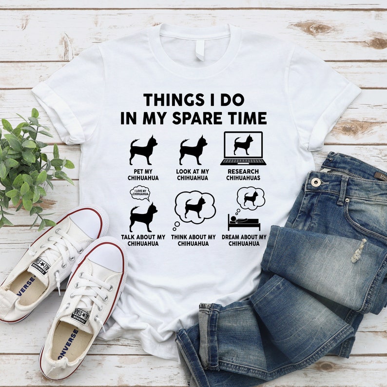 May include: White t-shirt with black text that reads "Things I do in my spare time". The text is surrounded by six black and white illustrations of a chihuahua dog. The illustrations depict the dog being petted, looked at, researched, talked about, thought about, and dreamed about.