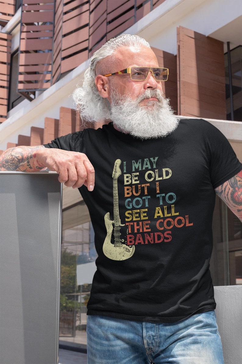 May include: A black t-shirt with a vintage-style graphic of a guitar and the text "I may be old but I got to see all the cool bands".