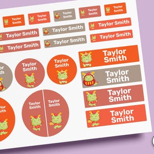 Könnte beinhalten: Ein Bogen mit rechteckigen und runden Aufklebern, die einen grünen Drachen und den Text Taylor Smith zeigen. Die Etiketten sind in verschiedenen Orange-, Rot- und Brauntönen gehalten, wobei einige Designs den Drachen in einem roten Outfit zeigen.