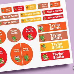Peut inclure: Une feuille d'étiquettes autocollantes rectangulaires et circulaires dans des tons de rouge, orange et marron. Chaque étiquette porte le nom Taylor Smith en blanc avec un petit dragon vert de dessin animé portant un chapeau.