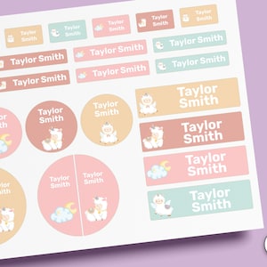 May include: A sheet of adhesive labels in various shapes and sizes, featuring the name Taylor Smith in white text. The stickers include illustrations of a white unicorn, clouds, and a crescent moon in pastel pink, peach, and mint green colours.