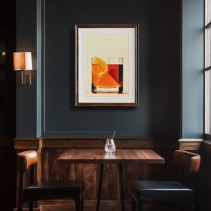 May include: A framed art print depicting a cocktail with an orange slice. The artwork is displayed on a dark teal wall above a wooden table with two chairs. A wall sconce and a window are also visible.