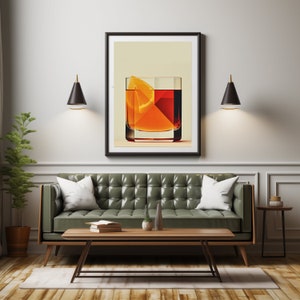May include: A framed art print depicting a cocktail with an orange slice. The artwork hangs above a green leather sofa with white pillows. A wooden coffee table and side table are in front of the sofa. Two black sconces flank the artwork.