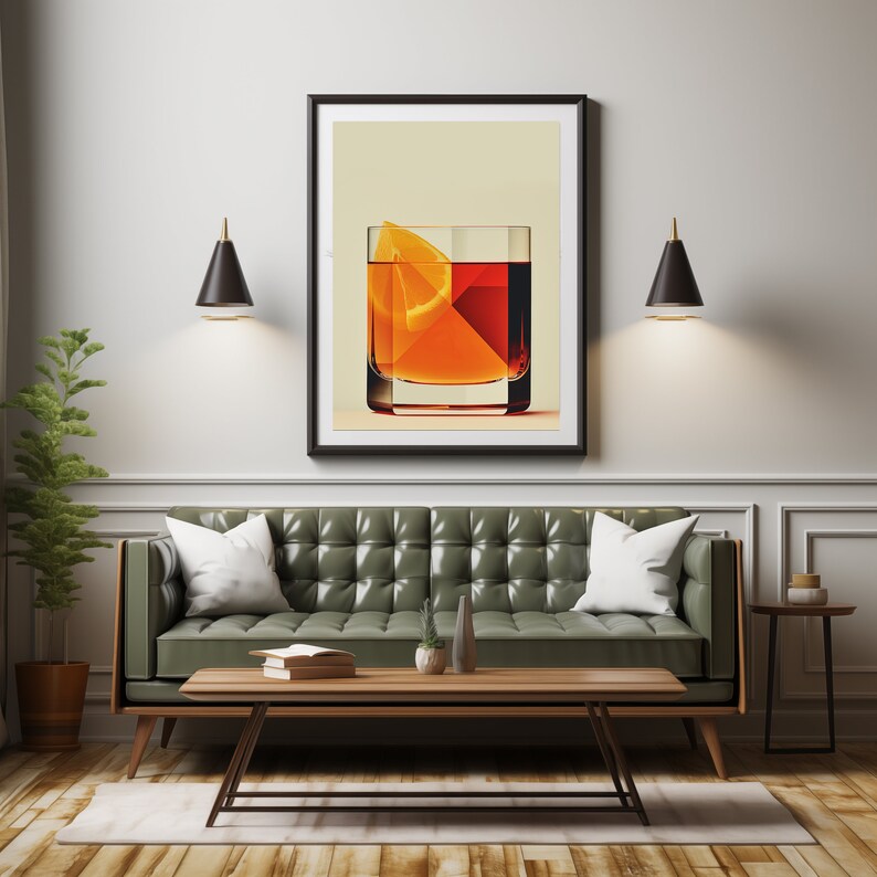 May include: A framed art print depicting a cocktail with an orange slice. The artwork hangs above a green leather sofa with white pillows. A wooden coffee table and side table are in front of the sofa. Two black sconces flank the artwork.