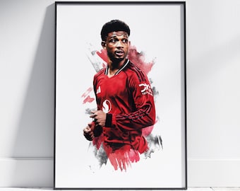 May include: Framed art print featuring a portrait of a soccer player in a red jersey. The artwork has a watercolor effect with red and black splashes. The player is looking to the side, with a determined expression.