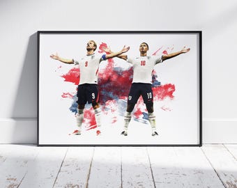 May include: A framed art print featuring two soccer players in white jerseys with red numbers 9 and 10 and dark blue shorts, arms outstretched, set against a red and blue watercolor-style splash background on a white surface.