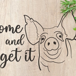Può includere: Un disegno in bianco e nero del viso di un maiale con il testo "Come and get it" su uno sfondo di legno. Nell'angolo in alto a destra dell'immagine ci sono delle erbe verdi.