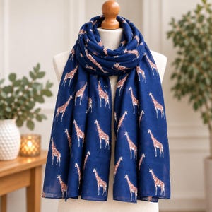 May include: A navy blue scarf featuring a repeating pattern of brown and white giraffes. The scarf is draped in multiple layers around a mannequin neck, displaying the full length of the fabric with the giraffe print visible across the entire surface.