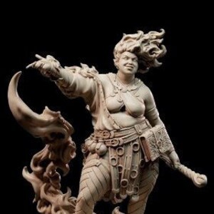 May include: A hand-painted ceramic figurine of a woman with fiery red hair, wearing a brown tunic and holding a staff. She is standing on a base with flames around her.