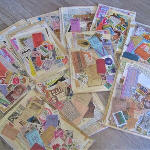 Puede incluir: Una colecci&oacute;n de ef&iacute;meras vintage, incluyendo boletos, sellos y recortes de papel, en varios colores y patrones. Las ef&iacute;meras est&aacute;n dispuestas en una pila sobre una superficie de madera.