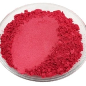May include: A close-up of a small bowl filled with a bright pink powder. The powder is fine and smooth, and it has a slight shimmer to it.