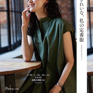 Pode incluir: Um vestido verde-oliva com gola mandarim e decote em V. A imagem apresenta texto japonês e etiquetas de tamanho. A modelo está sentada em uma mesa de madeira perto de uma janela. O texto no canto superior esquerdo diz "Heart Warming Life Series".
