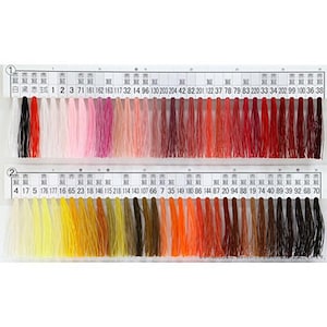 May include: A color chart featuring two rows of thread samples in a wide array of colors. The top row includes shades of black, red, pink, and brown. The bottom row displays yellow, orange, and brown hues. Each color is numbered.