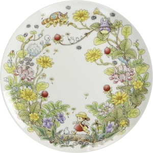 May include: White ceramic plate featuring a colorful illustration of a girl in a red dress, running through a floral meadow. The design includes yellow and pink flowers, strawberries, and cartoon characters. A whimsical and decorative plate.
