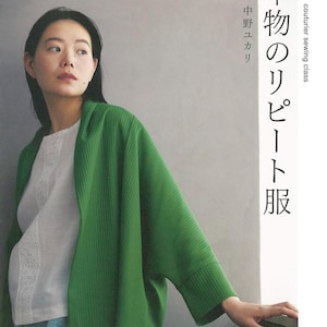 Puede incluir: Una mujer con un cárdigan verde sobre una camisa blanca con ribete de encaje. La imagen es de un libro titulado "couturier sewing class" con texto en japonés. La portada del libro presenta el texto "本物のリピート服".
