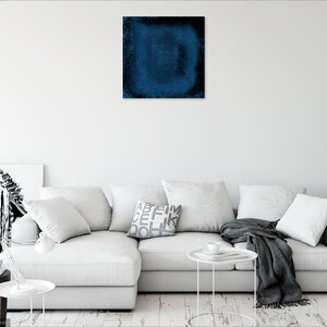 Puede incluir: Un sof&aacute; seccional blanco con una manta de tiro gris y una pintura abstracta azul en la pared encima. El sof&aacute; est&aacute; en un ambiente de sala de estar con una planta en una maceta y una mesa auxiliar.