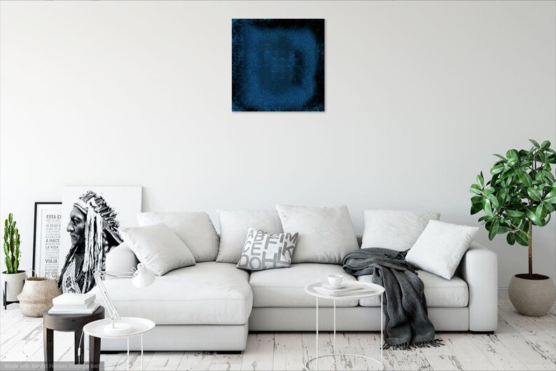 Puede incluir: Un sof&aacute; seccional blanco con una manta de tiro gris y una pintura abstracta azul en la pared encima. El sof&aacute; est&aacute; en un ambiente de sala de estar con una planta en una maceta y una mesa auxiliar.