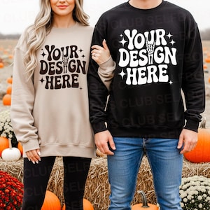 Könnte beinhalten: Zwei Sweatshirts, eines in Beige und eines in Schwarz, jeweils mit dem Text "YOUR DESIGN HERE" in einer Retro-Schriftart mit einer Handgeste. Das beige Sweatshirt wird mit schwarzen Leggings kombiniert, und das schwarze Sweatshirt wird mit Jeans kombiniert.