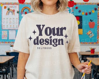 May include: Cream-colored t-shirt with the text "Your design" in dark blue, accented with starbursts. The word "SELFBOSS" is printed below the design. The shirt is short-sleeved and appears to be made of a soft material.