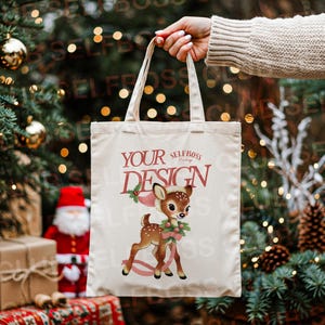 Peut inclure: Un sac fourre-tout crème avec un motif festif représentant un cerf de dessin animé avec une couronne de houx. Le sac porte l'inscription "YOUR DESIGN" en bordeaux. L'arrière-plan comprend un sapin de Noël et des décorations de vacances.