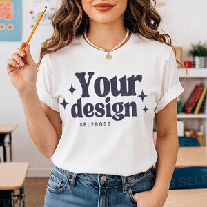 May include: White t-shirt with rolled sleeves featuring the text "Your design" in a dark blue font, with star accents. The word "SELFBOSS" is below the design. The person is wearing blue jeans and a pearl necklace.