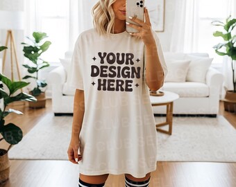 May include: A cream-coloured t-shirt featuring the text "YOUR DESIGN HERE" in dark brown, with starburst accents. The shirt is worn by a person in a bright room. The person is wearing black and white striped knee socks.