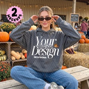 May include: A charcoal gray hooded sweatshirt featuring the white text Your here Design and the word SELFBOSS printed on the front. The garment has long sleeves, a front kangaroo pocket, and a drawstring hood, worn with blue denim jeans.
