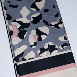 May include: A gray, black, and pink patterned scarf with a black and white striped border.