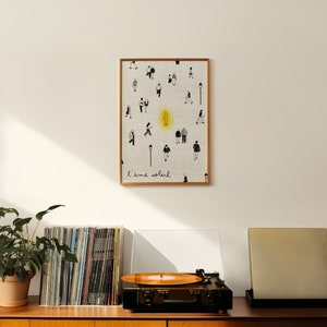 Peut inclure: Un meuble en bois de style mi-siècle moderne avec un tourne-disque et une estampe encadrée de silhouettes noires et blanches avec le texte "J'aime soleil" sur fond blanc.