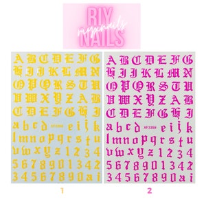 May include: Two sheets of nail stickers with an old English alphabet, numbers, and symbols. The stickers are yellow on a white background on the left sheet and pink on a white background on the right sheet. The text "riyxnails NAILS" is printed in pink on a white background at the top of the image.