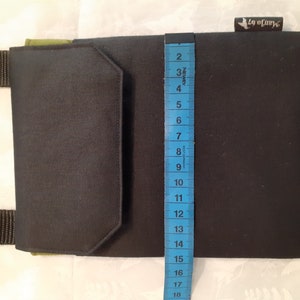 May include: A black and green canvas crossbody bag with a flap closure and a small pocket on the front. The bag is 18 inches tall.