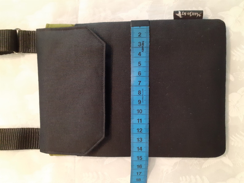 May include: A black and green canvas crossbody bag with a flap closure and a small pocket on the front. The bag is 18 inches tall.
