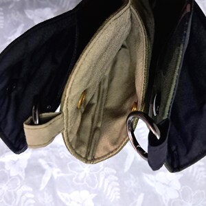 May include: Close-up of three small, open pouches in black, olive green, and tan. Each pouch has a metal ring and a snap closure. The pouches are made of a sturdy fabric and appear to be part of a larger bag or accessory.