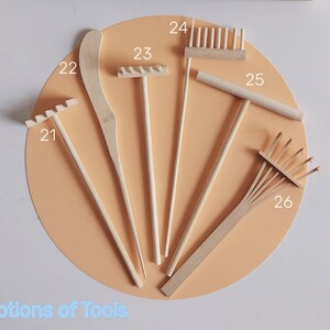May include: A set of seven wooden gardening tools, including rakes, a trowel, and a hand rake. The tools are labelled with numbers 21 to 26.