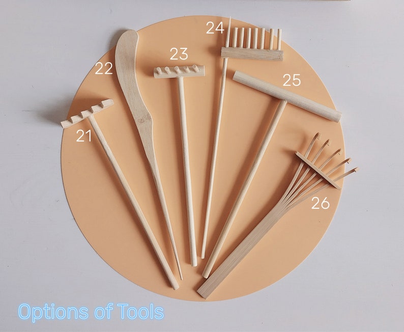 May include: A set of seven wooden gardening tools, including rakes, a trowel, and a hand rake. The tools are labelled with numbers 21 to 26.