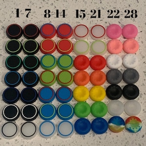 May include: A set of 28 colorful round controller thumbsticks. The thumbsticks are arranged in rows of four, with each row labeled 1-7, 8-14, 15-21, and 22-28.
