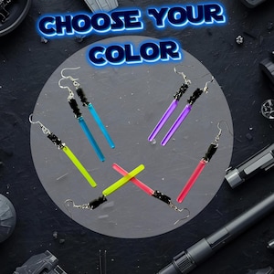 May include: Earrings with a lightsaber design in various colors: blue, purple, green, and red. The earrings have a black handle and silver hooks. The text "CHOOSE YOUR COLOR" is displayed in blue neon.