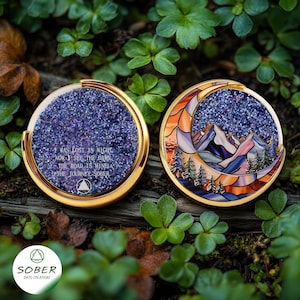 May include: Two round, gold-rimmed medallions. One features a glittery purple surface with the text "I WAS LOST IN NIGHT, NOW I SEE THE DAWN, THE ROAD IS MINE, THE JOURNEY SOBER." The other depicts a mountain scene within a crescent moon.