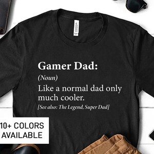 May include: Black t-shirt with white text that reads "Gamer Dad: (Noun) Like a normal dad only much cooler. [See also: The Legend, Super Dad]"  10+ COLORS AVAILABLE