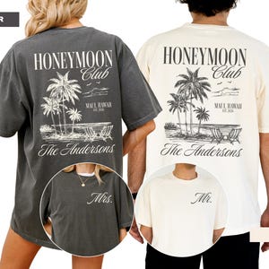 a couple wearing matching t-shirts with the text "Honeymoon Club" printed on them.