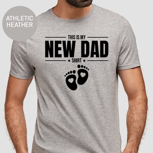 a man wearing a t - shirt that says, this is my new dad shirt