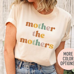 a woman wearing a t - shirt that says mother the mothers