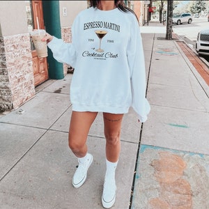 a woman walking down a sidewalk while holding a cup of coffee