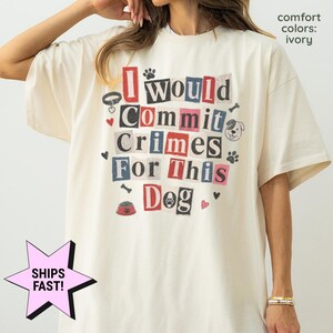 May include: An ivory t-shirt featuring a ransom note style graphic that reads I would Commit Crimes For This Dog. The design includes small illustrations of a dog collar, a dog face, paw prints, bones, hearts, and a food bowl in red and black.