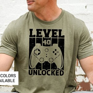May include: A green t-shirt with a black graphic that says "Level 40 Unlocked" and features a video game controller.