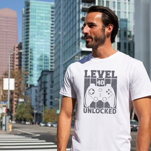 May include: White t-shirt with a gray graphic of a video game controller and the text "LEVEL 40 UNLOCKED".