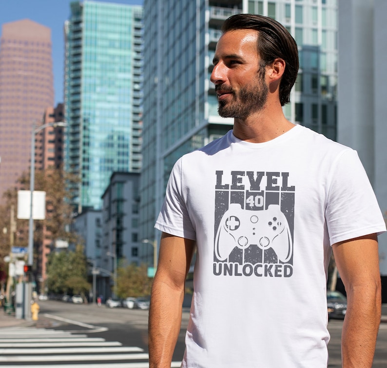 May include: White t-shirt with a gray graphic of a video game controller and the text "LEVEL 40 UNLOCKED".