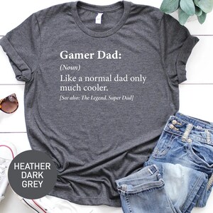May include: Heather dark grey t-shirt with the text "Gamer Dad: (Noun) Like a normal dad only much cooler. [See also: The Legend, Super Dad]" printed in white.